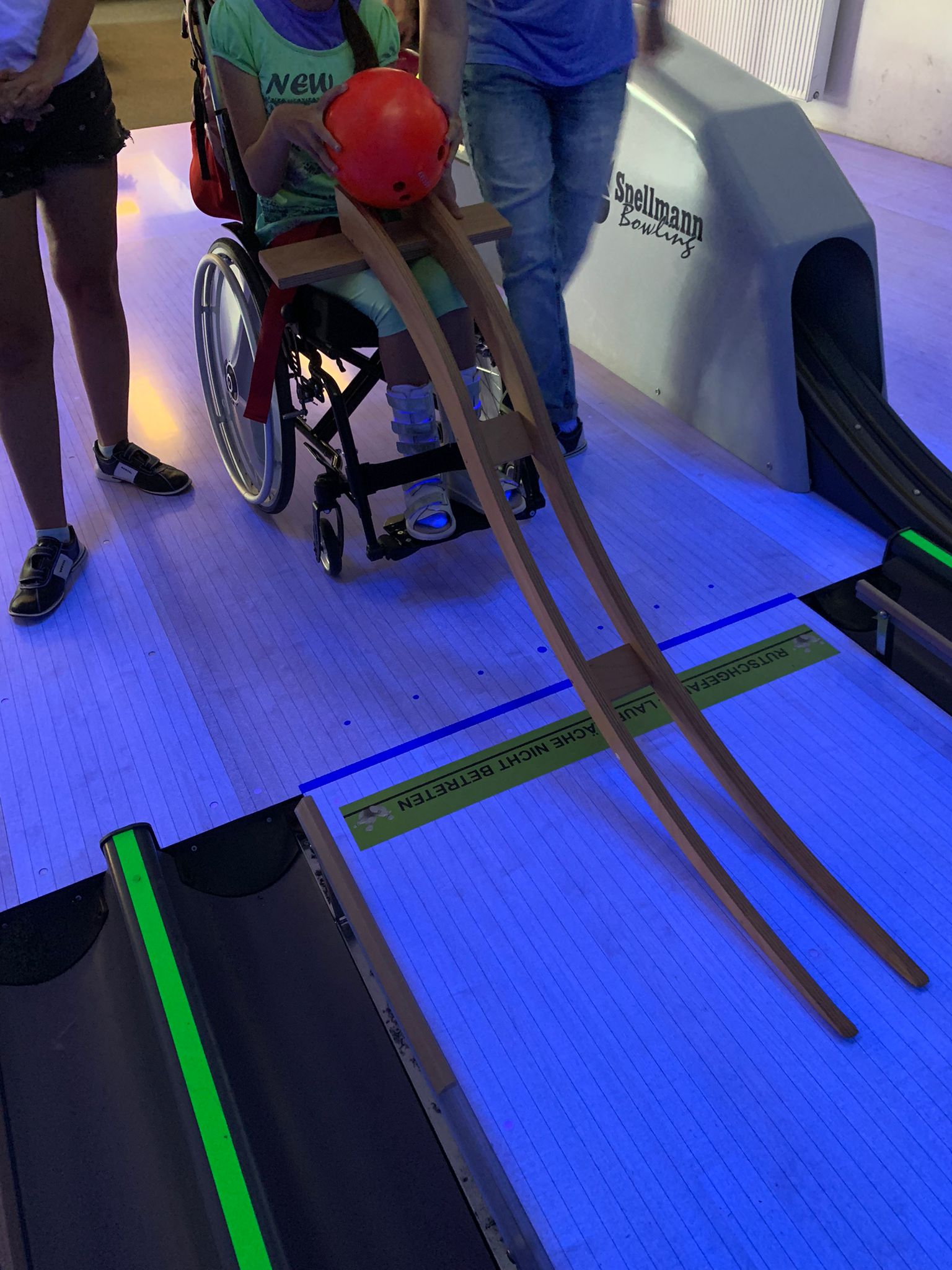 Sch%C3%BClerin%20im%20Rollstuhl%20mit%20Wurfhilfe%20beim%20Bowlen